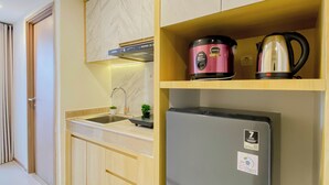 A kitchen with a built-in sink, a stainless steel refrigerator, a microwave, and a kettle on the countertop.