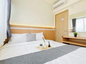 Ein Hotelzimmer mit Bett, Nachttisch, Klimaanlage und einem Vorhangfenster.