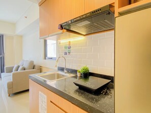 Eine moderne Küche mit Spüle aus Edelstahl, einem schwarzen Induktionskochfeld und Holzschränken.