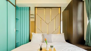 Habitación de hotel con cama, una bandeja con una flor, un jarrón y una planta pequeña.