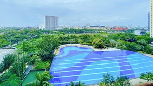 A large outdoor swimming pool with a blue and white design, surrounded by lush greenery and modern buildings in the background. - Best Choice Studio At Springlake Summarecon Bekasi Apartment (Bekasi)