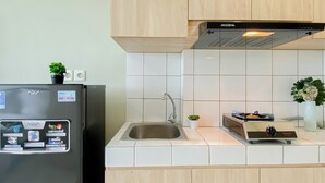 A kitchen with a black refrigerator, a built-in oven, a sink, and wooden cabinets. - Best Choice Studio At Springlake Summarecon Bekasi Apartment (Bekasi)