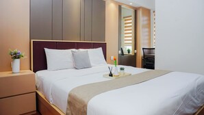 Een moderne hotelkamer met een groot bed, nachtkastjes, een spiegel en een zithoekje.