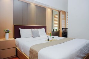 A modern hotel room with a large bed, bedside tables, a nightstand, a mirror, and a small seating area. - Enjoy Living 2Br At Springlake Summarecon Bekasi Apartment (Bekasi)