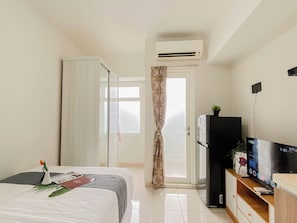 Camera d'albergo con un letto, una TV, un frigorifero e un condizionatore.