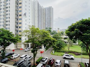 Un palazzo residenziale a più piani con numerosi balconi, un parcheggio pieno di automobili e vegetazione circostante.