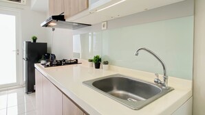 A modern kitchen with a stainless steel sink, a built-in stove, and a range hood. - Nice And Tidy Studio Room At Apartment Springlake Summarecon Bekasi (Bekasi)
