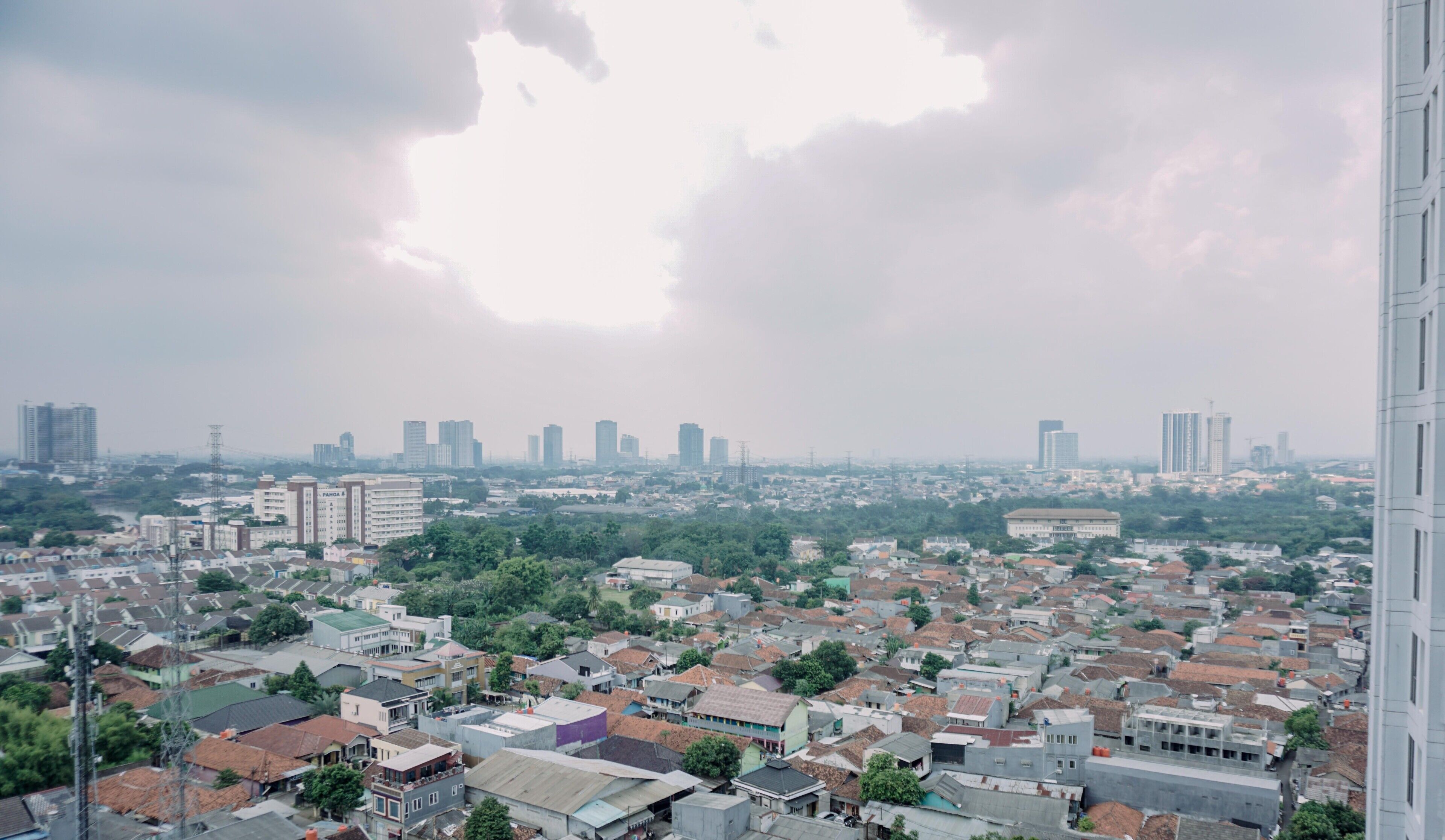 Un paisaje urbano con edificios residenciales densos, algunas estructuras altas y una gran nube en el cielo.