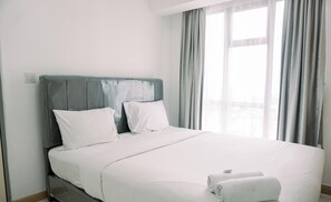 Habitación de hotel con una cama, dos almohadas, cabecero y una ventana con cortinas.