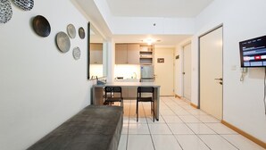A modern kitchen with a dining area, a bench, and a TV mounted on the wall. - Simple 2Br Space At Apartment M-Town Residence (Gading Serpong)