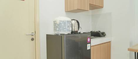 A compact kitchen with a refrigerator, a kettle, and a toaster on the counter.