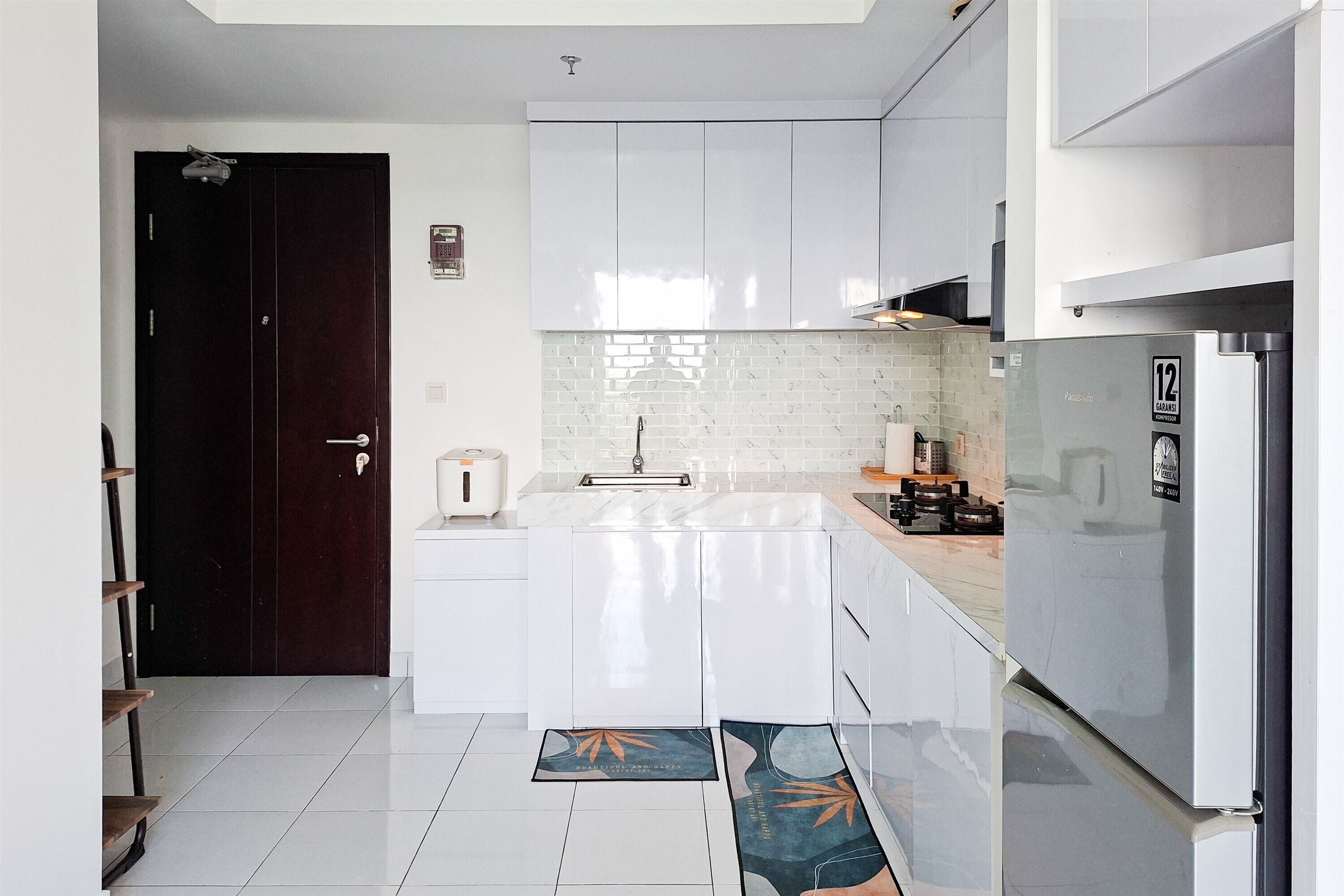 A modern kitchen with white cabinets, a stainless steel refrigerator, and a tiled backsplash.