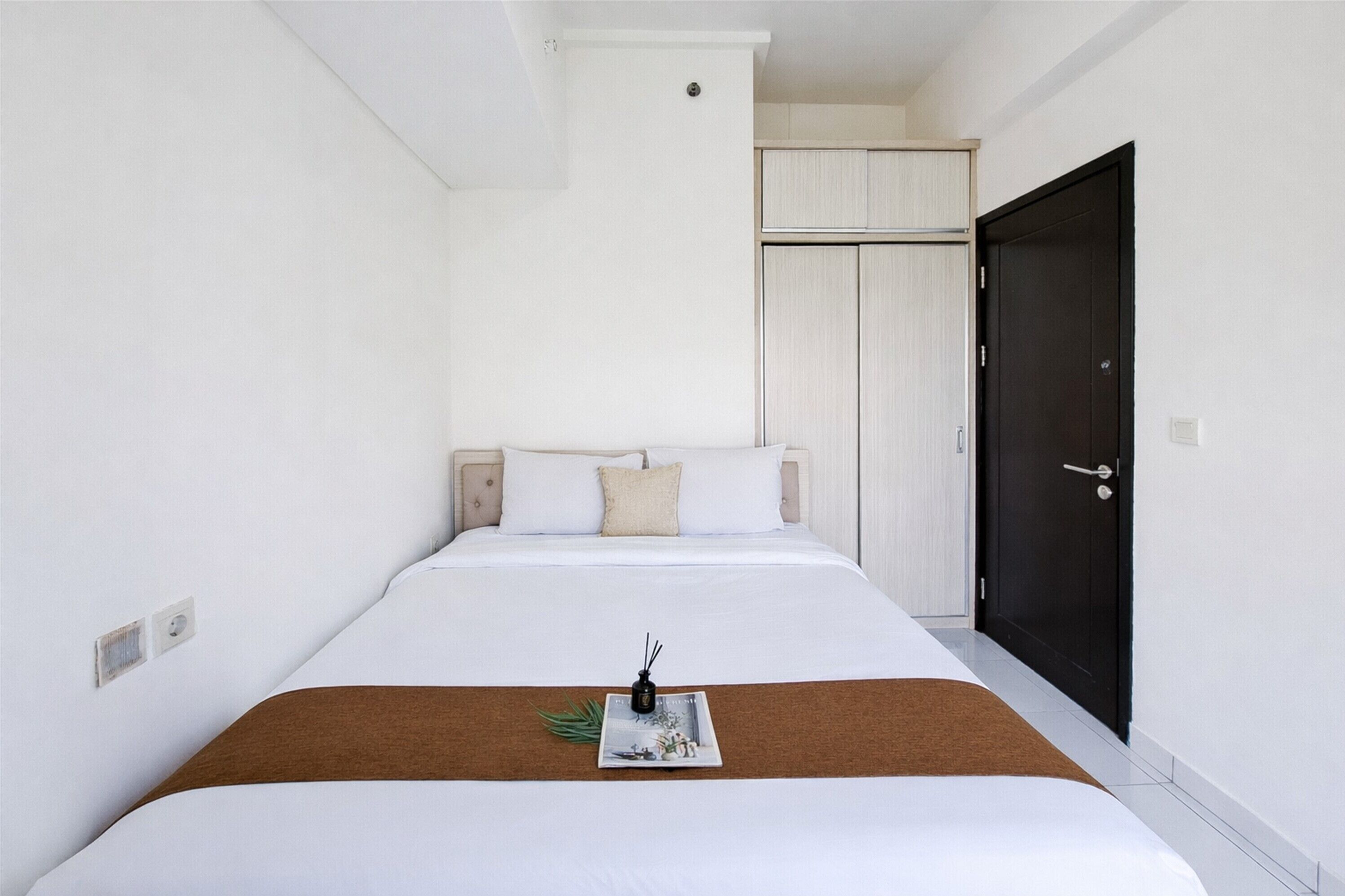 A hotel room with a bed, a dark door, and a white wardrobe.