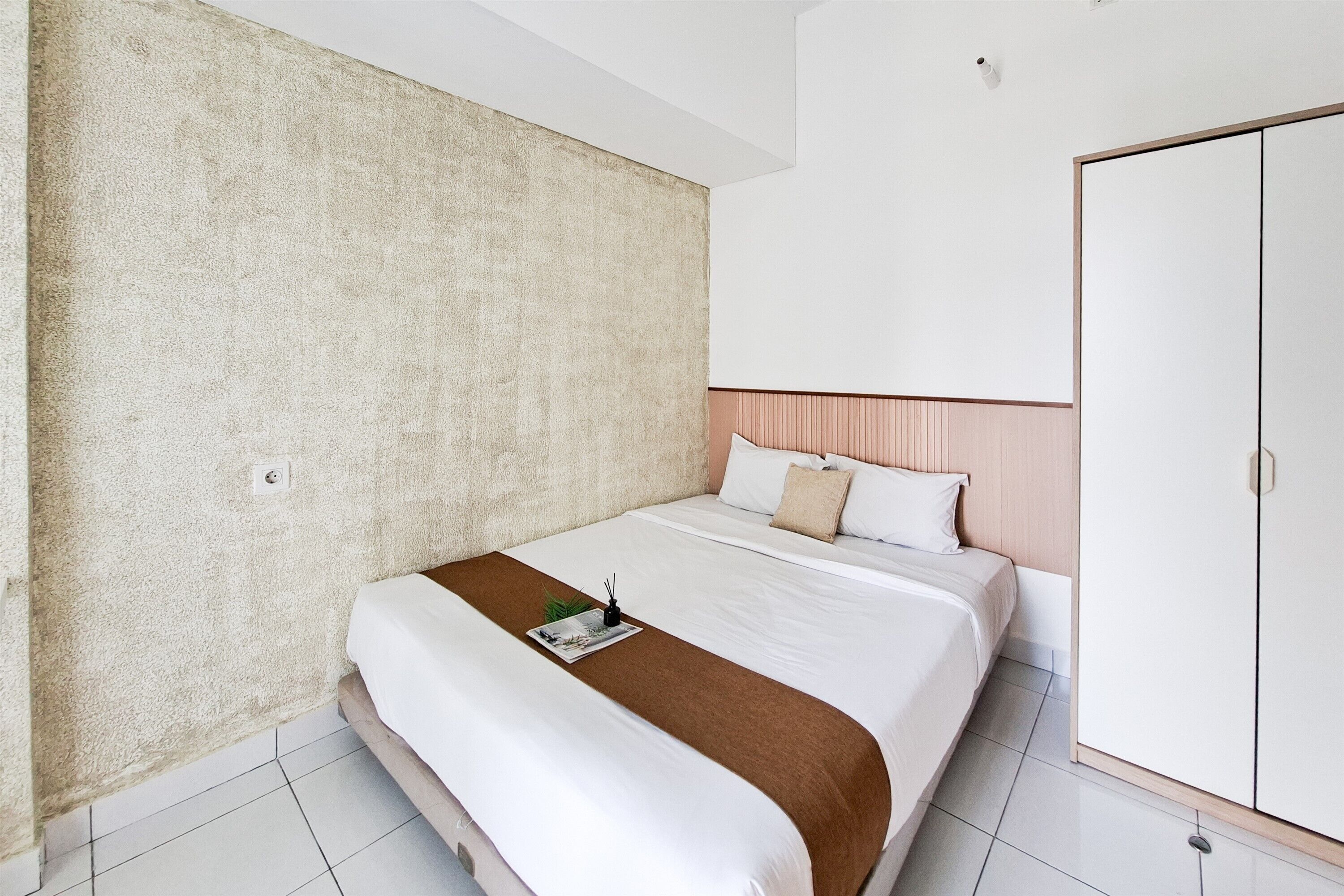 A hotel room with a large bed, a wardrobe, and a textured wall.