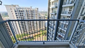 A balcony with a metal railing, a tiled floor, and a view of surrounding high-rise buildings. - Calm And Casual Living 1Br At Casa De Parco Apartment (Pagedangan)