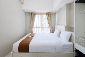 A modern hotel room with a large bed, a bedside table, and a wardrobe. - Calm And Casual Living 1Br At Casa De Parco Apartment (Pagedangan)