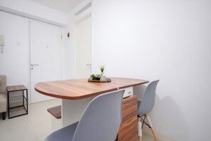 A modern dining area with a wooden table, grey chairs, and a small plant on the table. - Strategic And Homey 2Br At Bassura City Apartment (Jakarta)