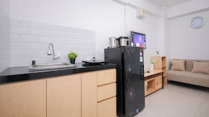 A modern kitchen with a black refrigerator, a sink, and a small potted plant. - Strategic And Homey 2Br At Bassura City Apartment (Jakarta)