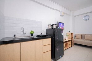 Et moderne køkken med et sort køleskab, en vask og en lille potteplante.
