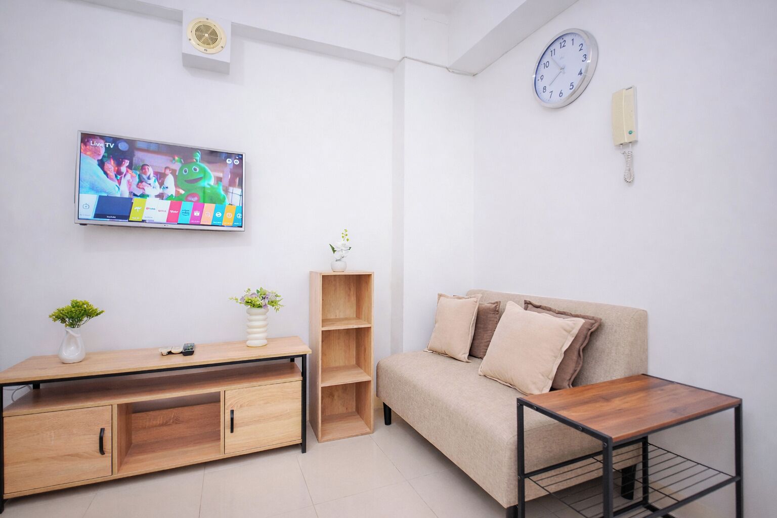 A modern living room with a TV, sofa, coffee table, and a wooden cabinet.