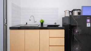 A modern kitchen with a black refrigerator, a stainless steel kettle, and a small potted plant on the counter. - Strategic And Homey 2Br At Bassura City Apartment (Jakarta)