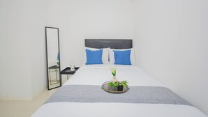 A neatly arranged hotel room with a bed, a bedside table, a mirror, and a tray with plants. - Strategic And Homey 2Br At Bassura City Apartment (Jakarta)