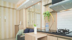 A modern kitchen with a gas stove, a countertop, and a mirror above the sink. - Warm 2Br For 3 Pax At Bassura City Apartment Near Shopping Center (Jakarta)