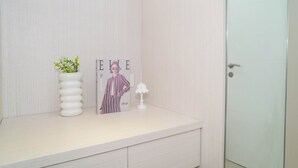 A bathroom vanity with a striped magazine, a potted plant, and a lamp. - Warm 2Br For 3 Pax At Bassura City Apartment Near Shopping Center (Jakarta)