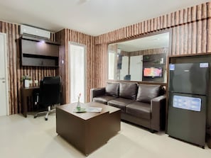 Una sala de estar moderna con sofá, mesa de centro, televisor y refrigerador.