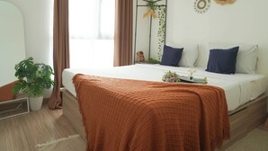 A bedroom with a bed, a bedside plant, a mirror, and a wall decoration. - Homey 2Br For 3 Pax At Sky House Bsd Apartment (Pagedangan)