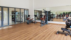 A gym with exercise equipment, large mirrors, and wooden flooring. - Studio Japandi Areum Residence At Sky House Bsd (Pagedangan)
