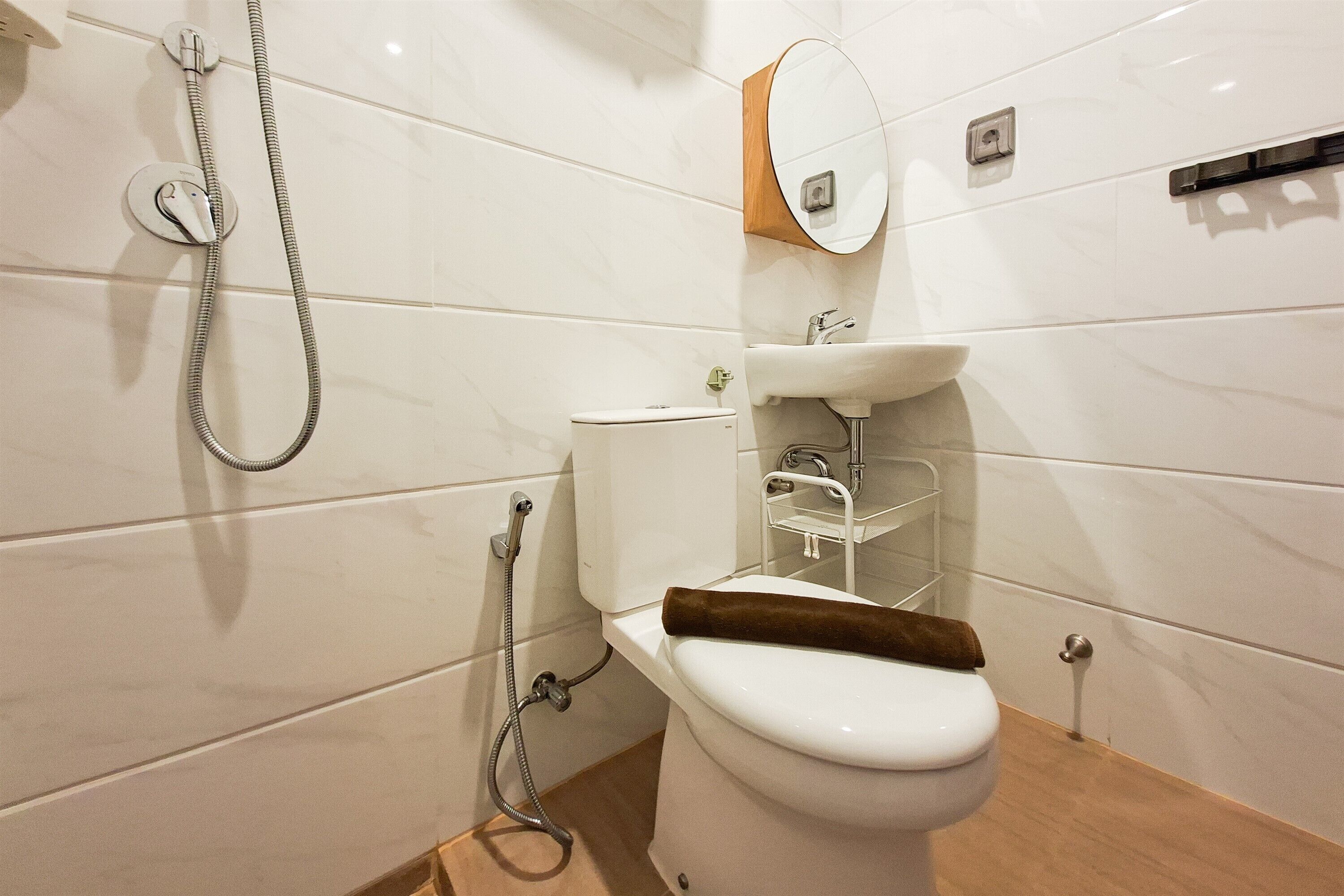 A modern bathroom with a toilet, a shower, a sink, and a mirror.