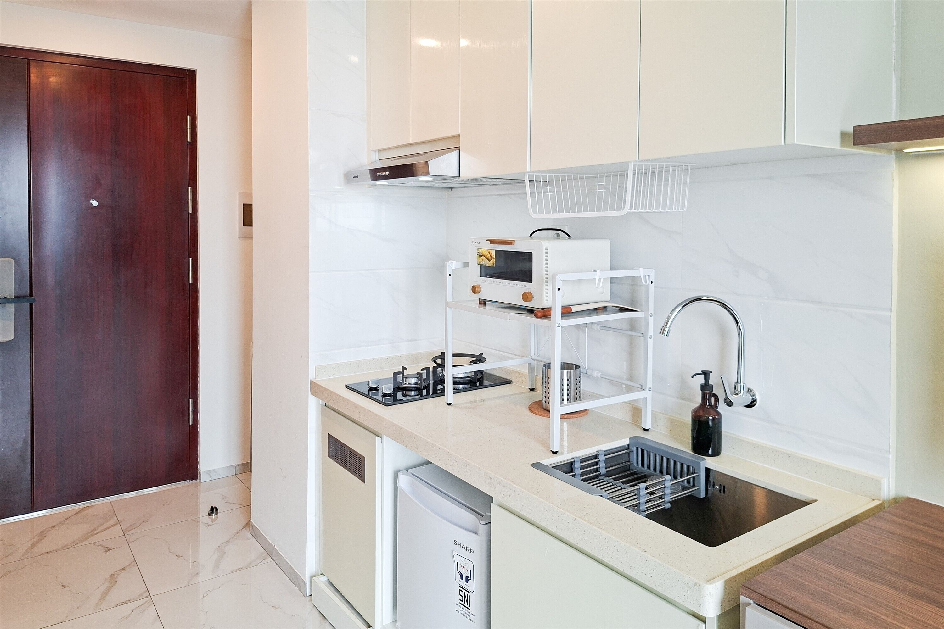 A compact kitchen with a built-in oven, a sink, and a compact dishwasher.