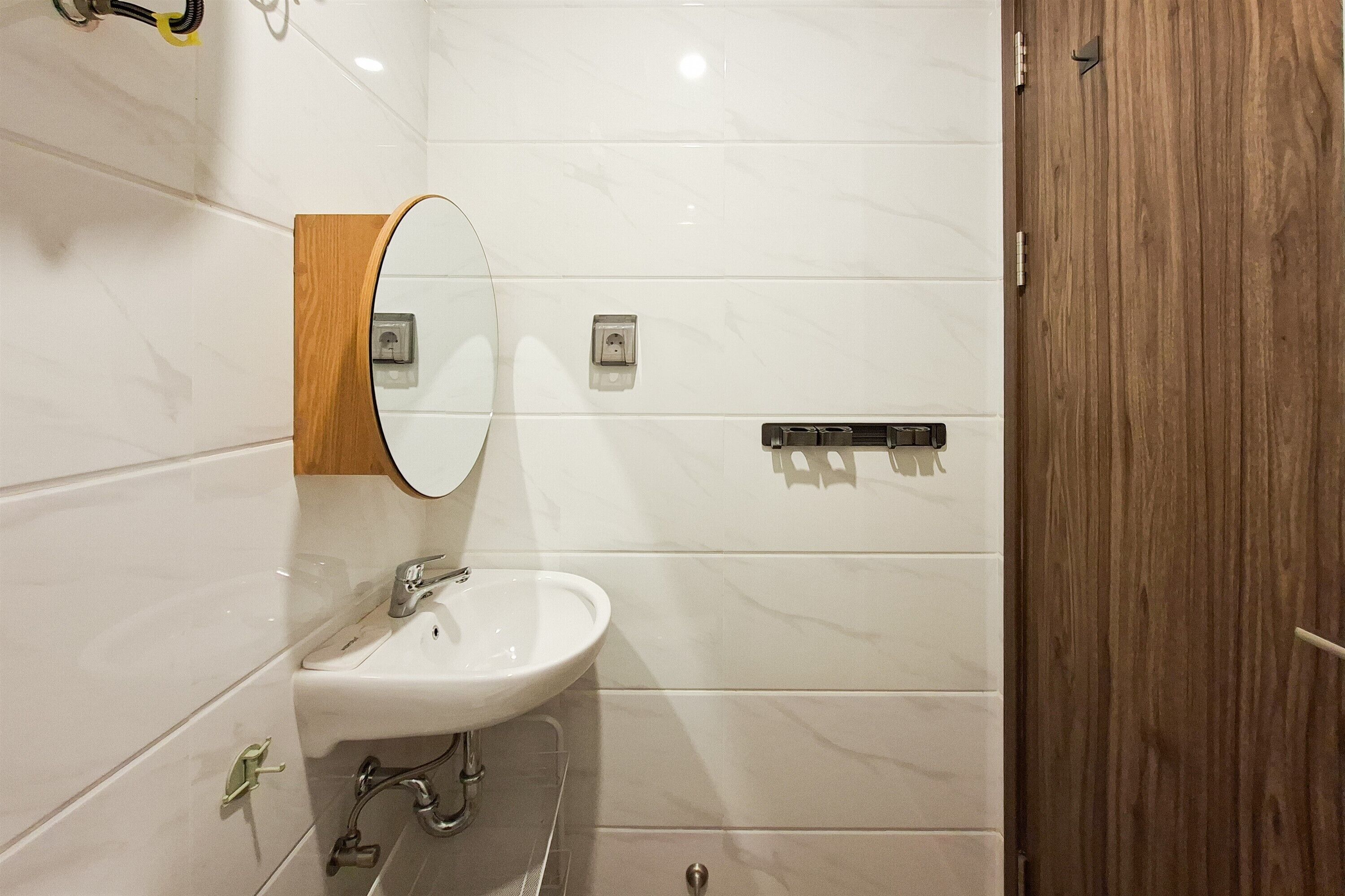 A bathroom with a white sink, a mirror, and a wooden door.