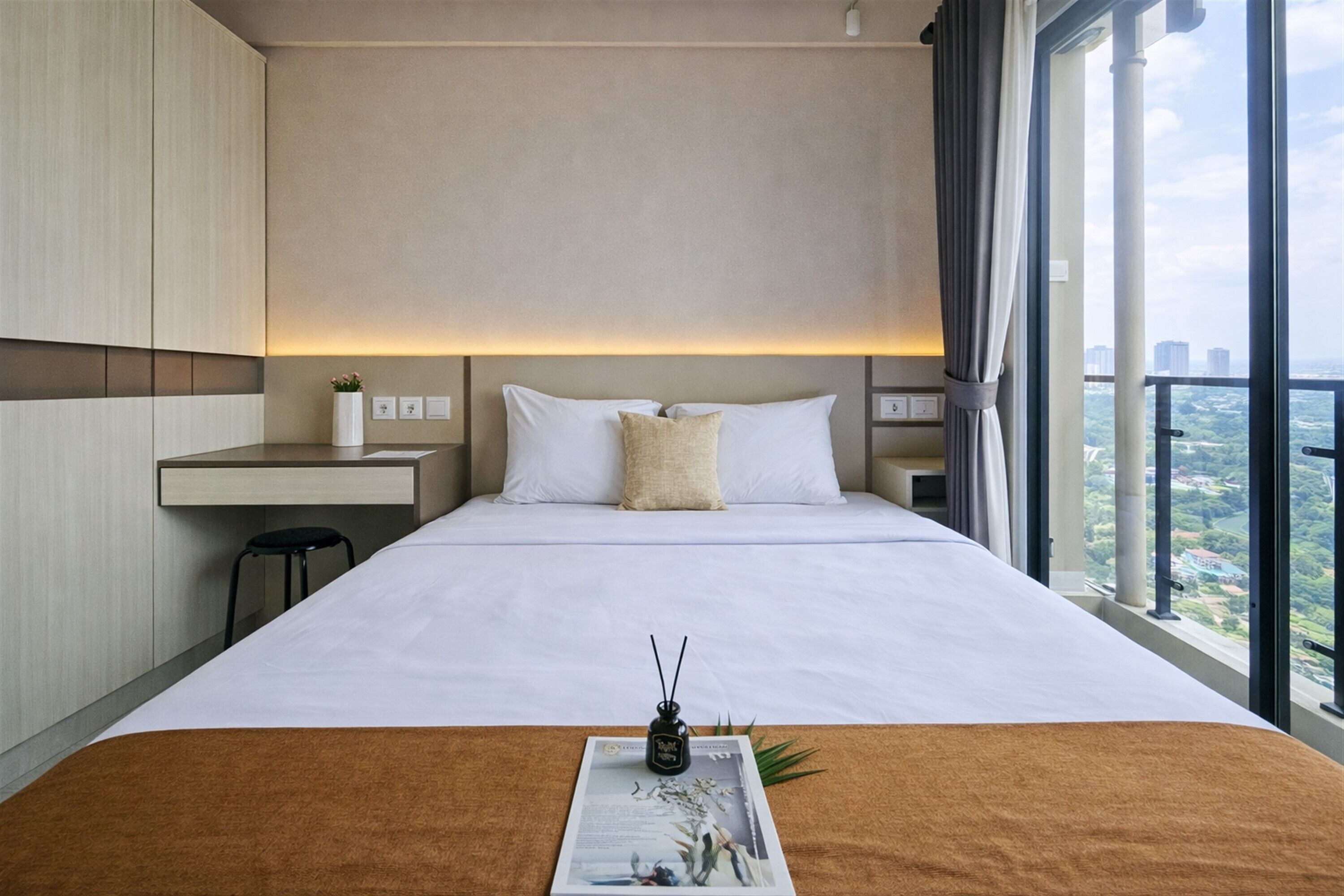A hotel room with a large bed, a desk, and a view of the city.