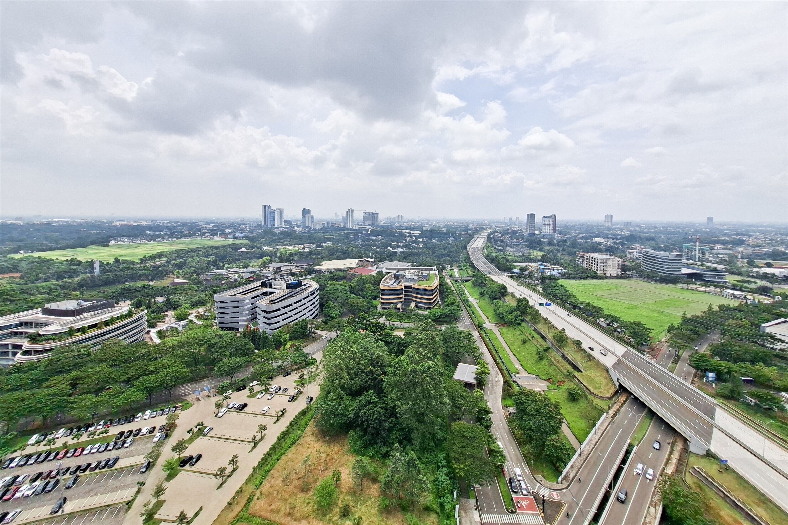 Une vue aérienne d’une ville avec ses bâtiments modernes, une autoroute et des espaces verts.