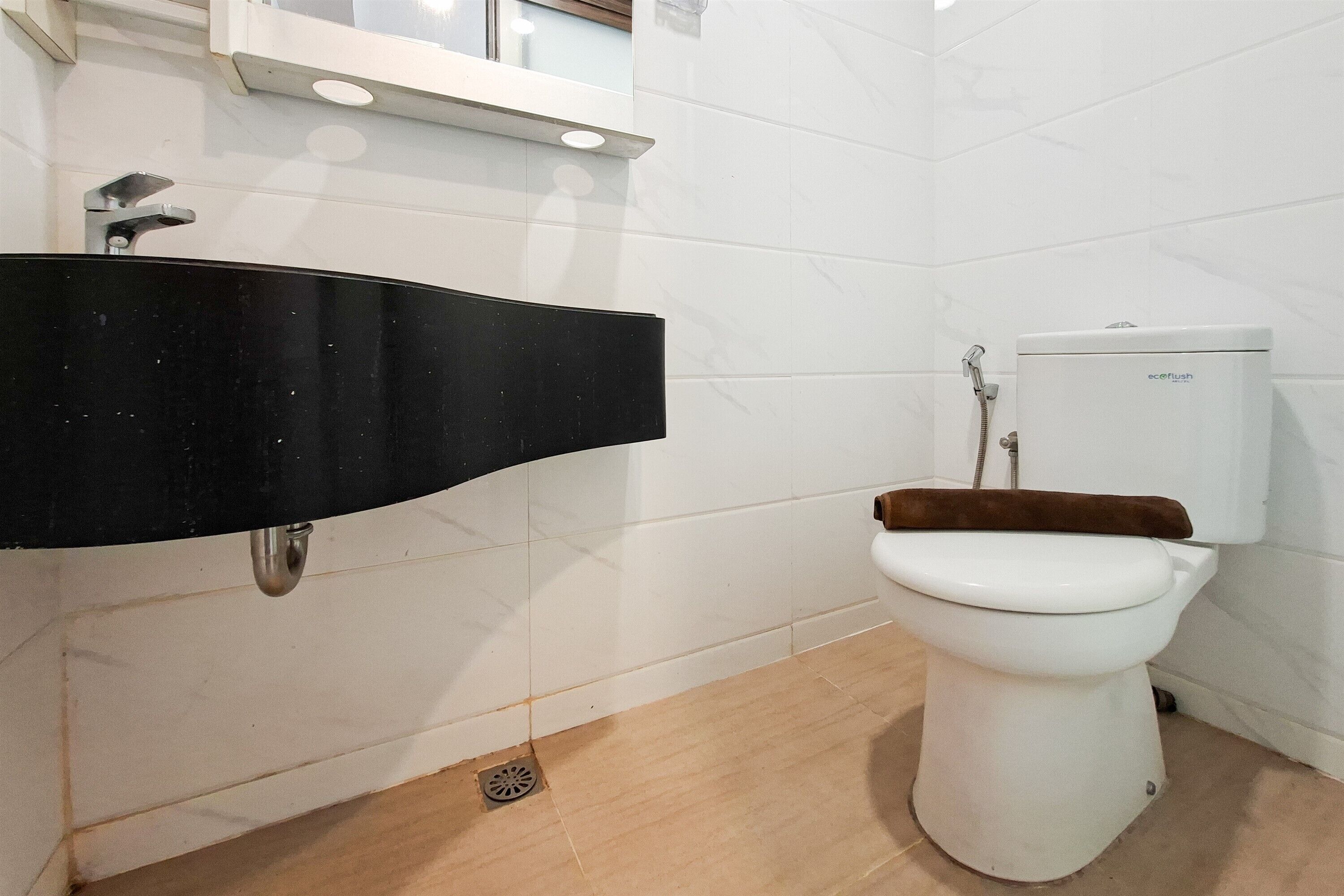 A bathroom with a black sink, white toilet, and a shower area.