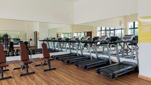 A gym with treadmills, benches, and a mirrored wall. - Bright And Homey Studio Room At Apartment Sky House Bsd (Balaraja)