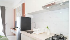 A modern kitchen with a black refrigerator, a sink, a stove, and a white countertop. - Bright And Homey Studio Room At Apartment Sky House Bsd (Balaraja)