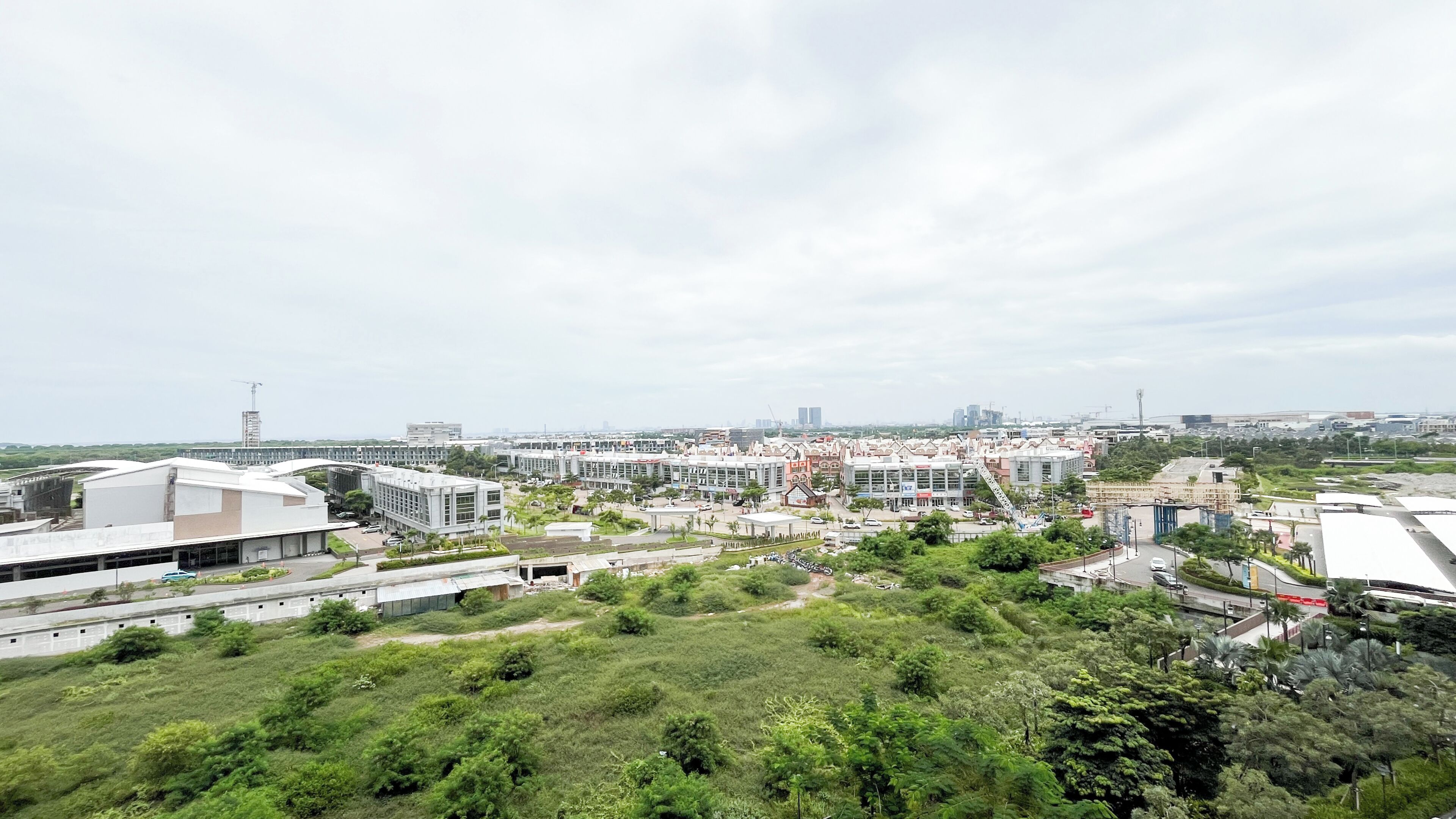 Un área urbana moderna con una combinación de edificios comerciales y residenciales, espacios verdes y cielo despejado.