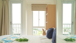 A hotel room with a bed, a window, and a balcony. - Cozy White Studio For 2 Pax At Tokyo Riverside Pik 2 Apartment (Teluknaga)