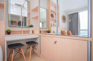A modern room with a large mirror, two black stools, a wooden cabinet, and a view of the city through a window.