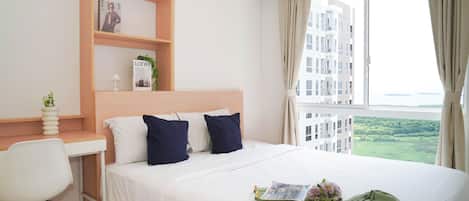 Une chambre d’hôtel avec un lit, un bureau et une fenêtre donnant sur des bâtiments et de la verdure.