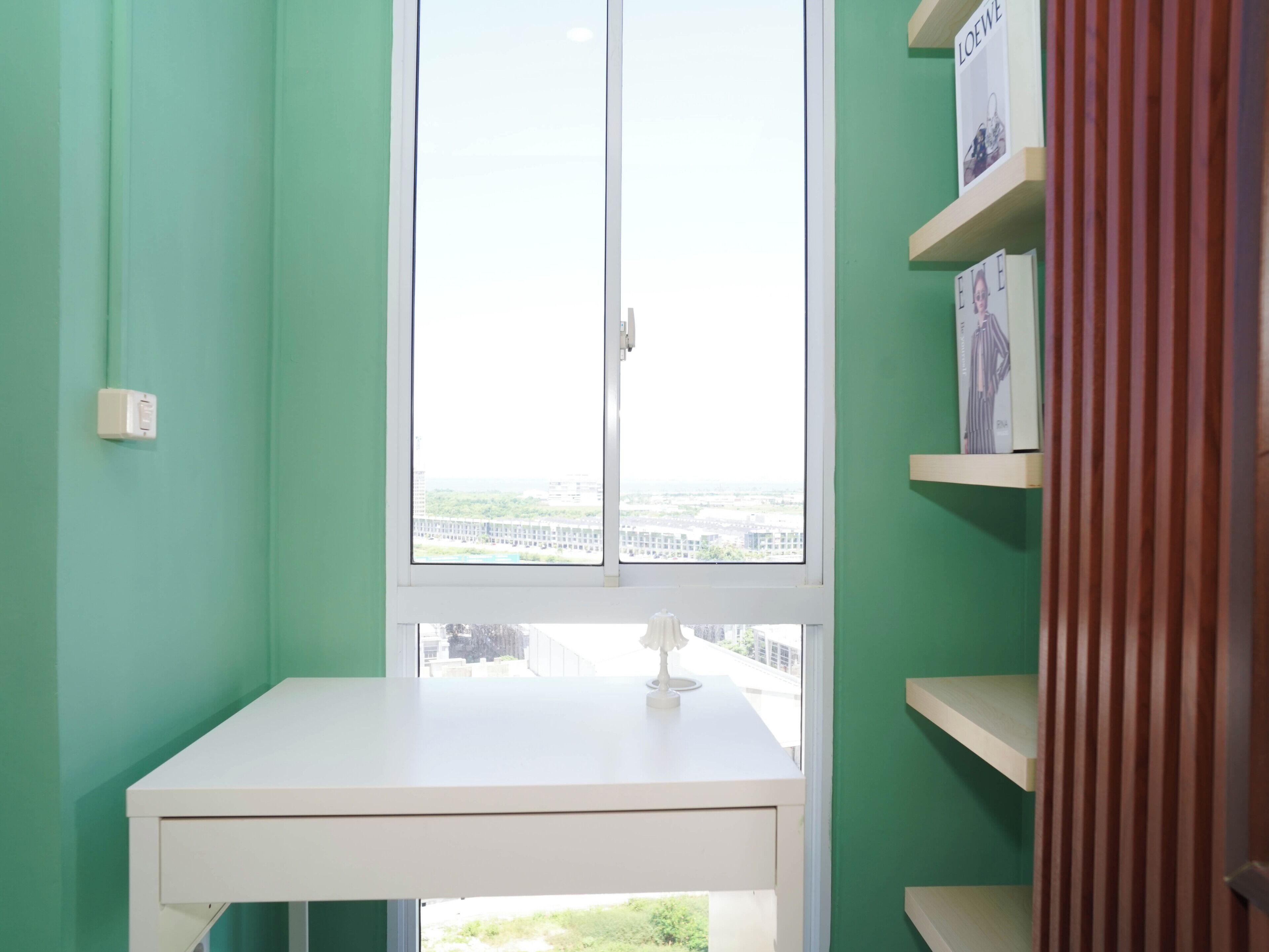 A room with a desk, a window, and a green wall.