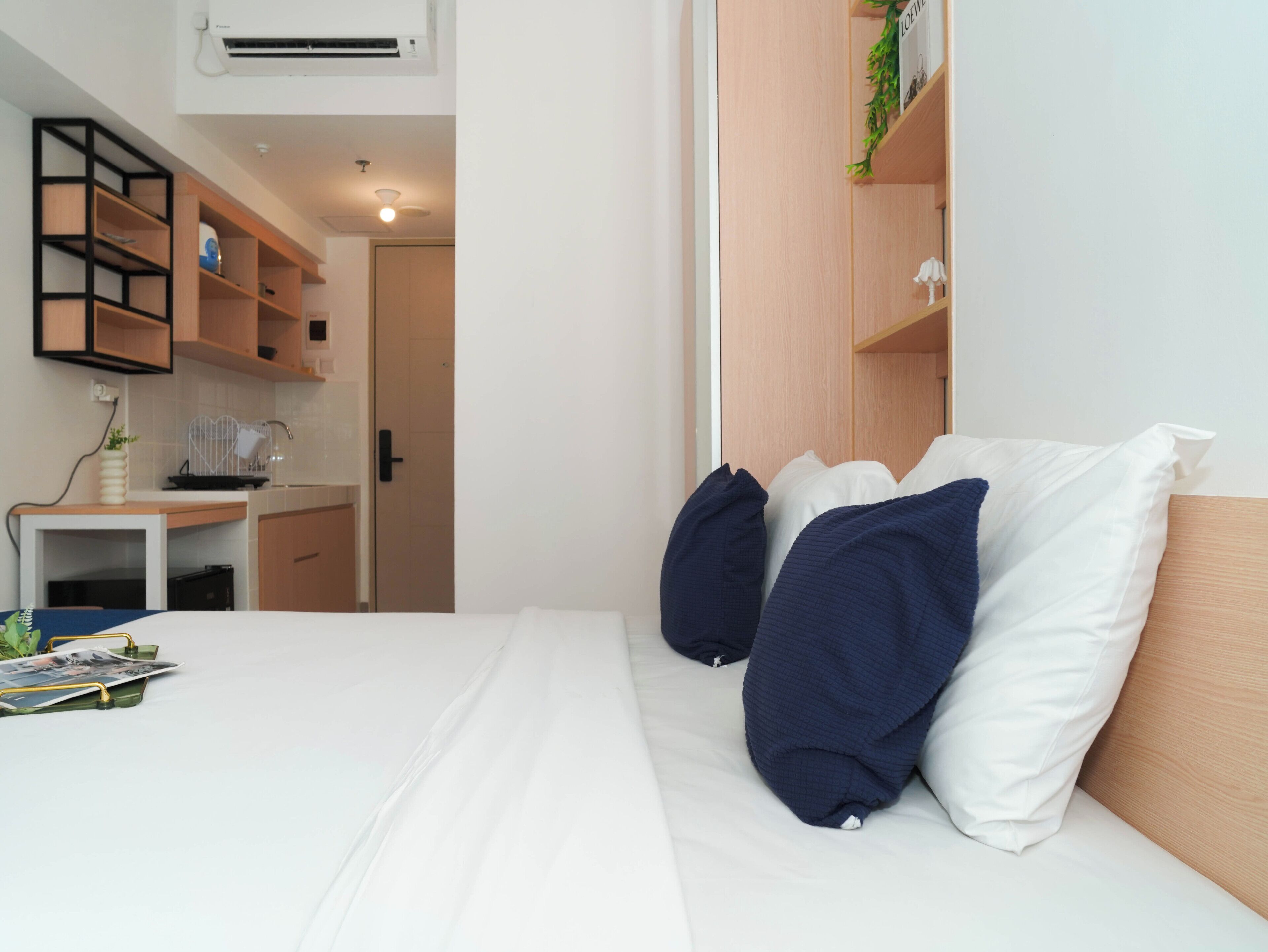 A bedroom with a bed, pillows, a desk, and a wardrobe.