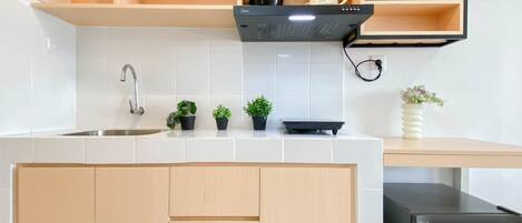 Una cocina con pileta, armarios, estufa y refrigerador.