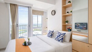 A hotel room with a bed, a TV, a clock, and a balcony with a view. - Practical Studio For 2 Pax At Tokyo Riverside Pik 2 Apartment Near Nice (Teluknaga)