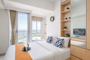 Une chambre d’hôtel avec un lit, une télévision, une horloge et un balcon offrant une vue.
