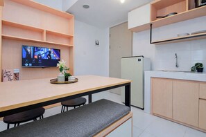 A modern kitchen with a built-in fridge, a dining table with chairs, and a TV on the wall. - Nice And Restful 2Br At Apartment Tokyo Riverside Pik 2 (Teluknaga)