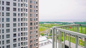 Un edificio alto con múltiples balcones, vista a un paisaje verde y una masa de agua al fondo.